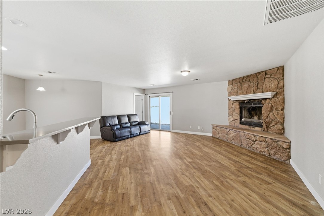 2780 West Simkins Road Pahrump, NV 89060 - Photo 6 of 40 A spacious living area featuring a striking stone fireplace and gleaming hardwood flooring.
