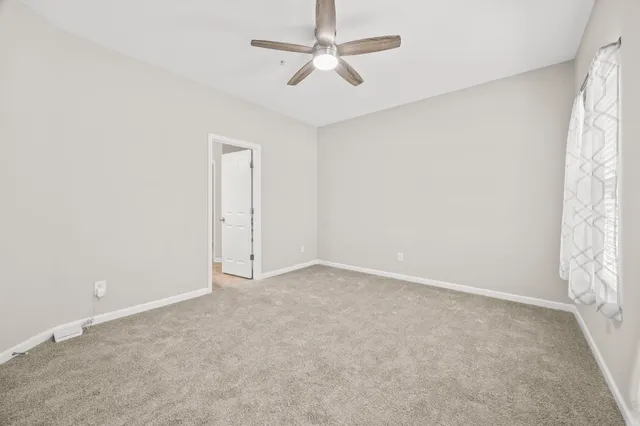 an empty room with windows and fan