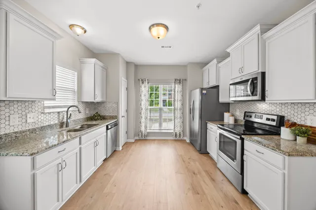 a kitchen with granite countertop a stove top oven a sink a counter space and cabinets