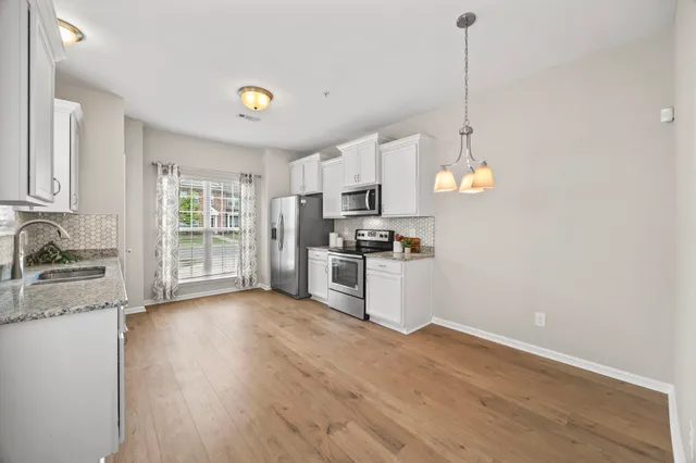 a kitchen with granite countertop a stove a sink a center island a refrigerator and a wooden floor