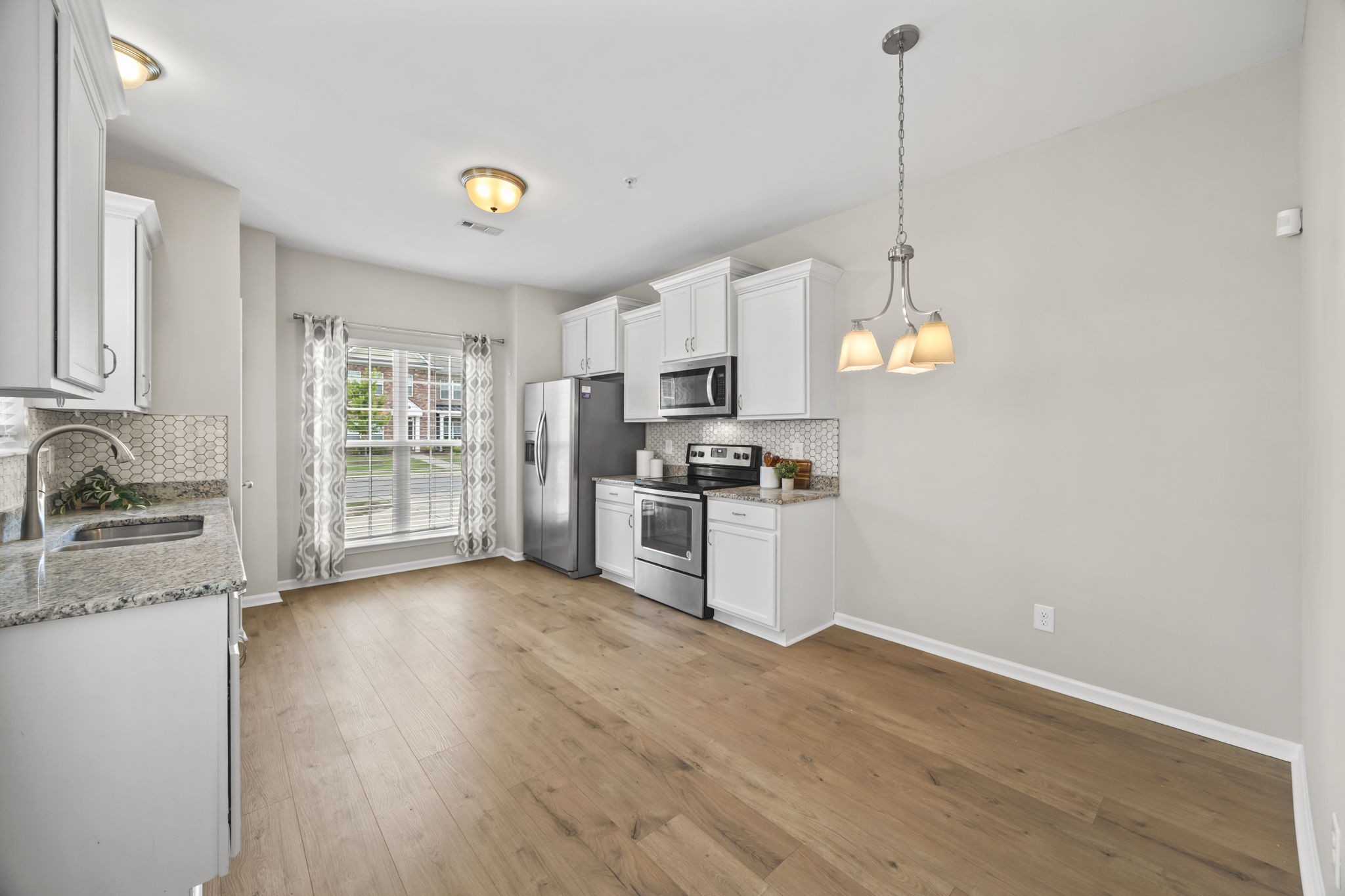 501 Shirebrook Circle Spring Hill, TN 37174 - Photo 5 of 26 a kitchen with granite countertop a stove a sink a center island a refrigerator and a wooden floor