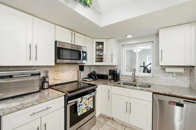a kitchen with granite countertop a sink a stove and cabinets