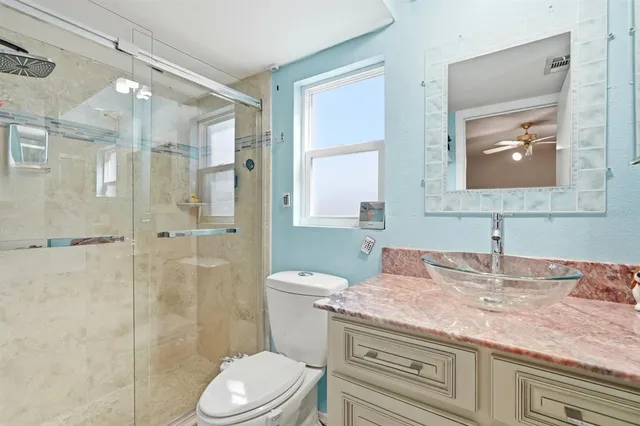 a bathroom with a granite countertop shower sink vanity mirror and toilet