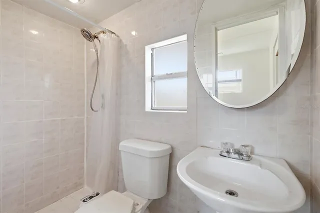 a bathroom with a sink a mirror a toilet and a shower