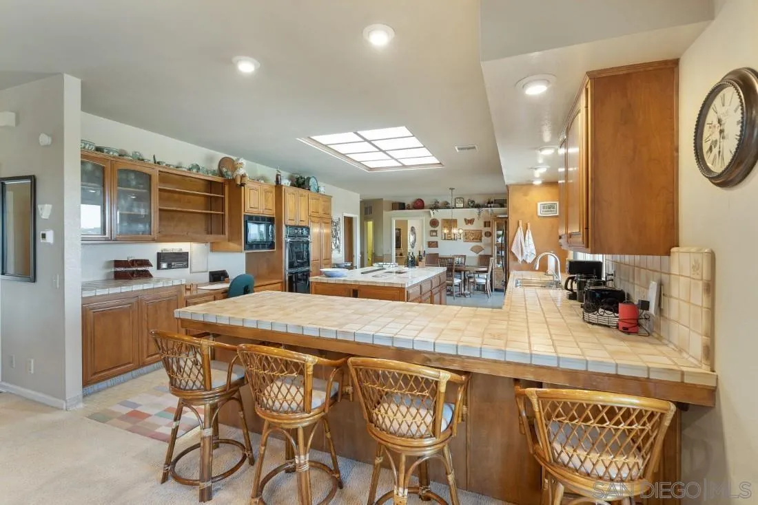 15938 Overview Road Poway, CA 92064 - Photo 48 of 72 a kitchen with stainless steel appliances granite countertop a sink a stove a refrigerator cabinets and chairs