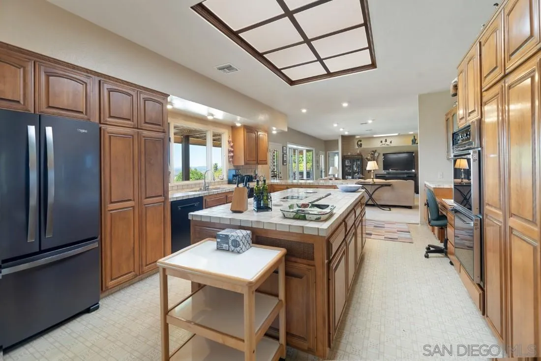 15938 Overview Road Poway, CA 92064 - Photo 51 of 72 a kitchen with stainless steel appliances kitchen island granite countertop a refrigerator a stove a sink a dining table and chairs with wooden floor