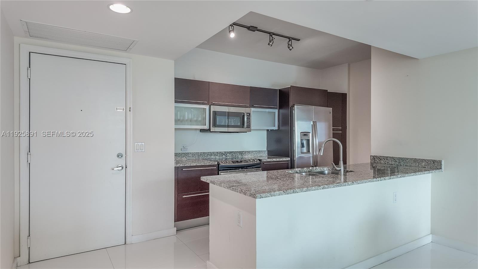 951 Brickell Avenue, Unit 1206 Miami, FL 33131 - Photo 2 of 12 a kitchen with stainless steel appliances granite countertop a sink and a refrigerator