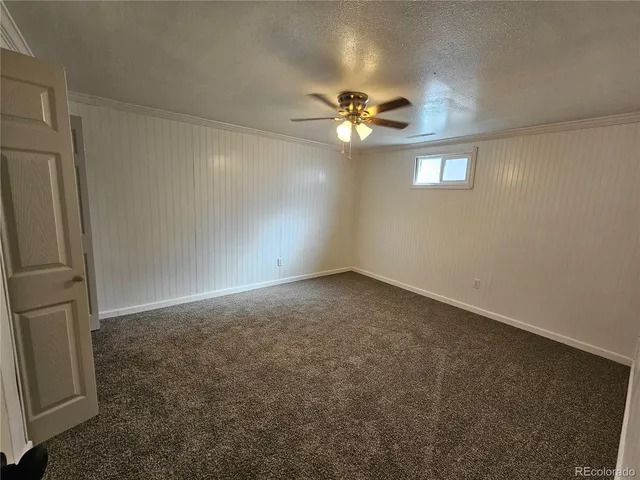 an empty room with a chandelier fan and windows