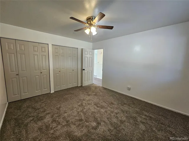 an empty room with closet and a ceiling fan
