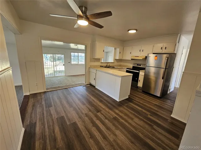 a kitchen with stainless steel appliances a refrigerator a sink dishwasher a stove and white countertops with wooden floor