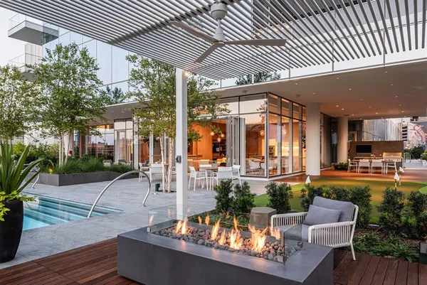 a view of a patio with couches table and chairs potted plants and a large tree
