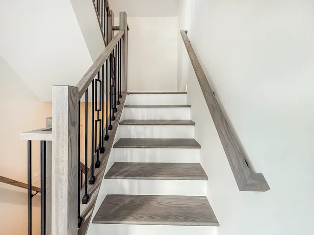 a view of staircase with white walls and a rug