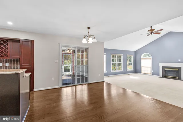 a view of an empty room with window and a kitchen view