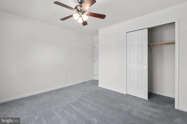an empty room with windows and chandelier fan