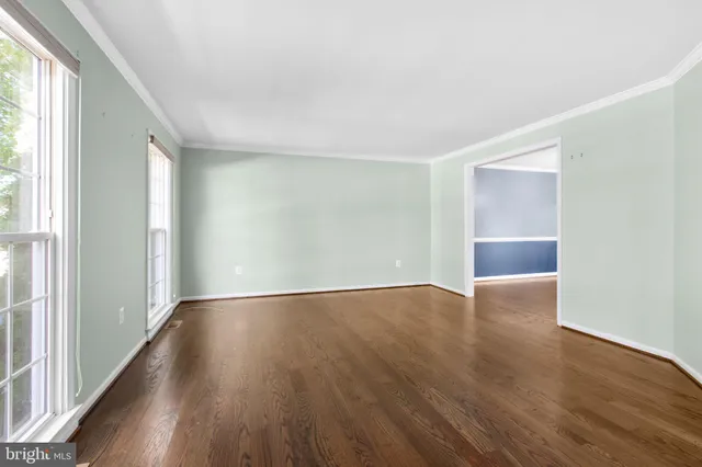 a view of an empty room with wooden floor and stairs