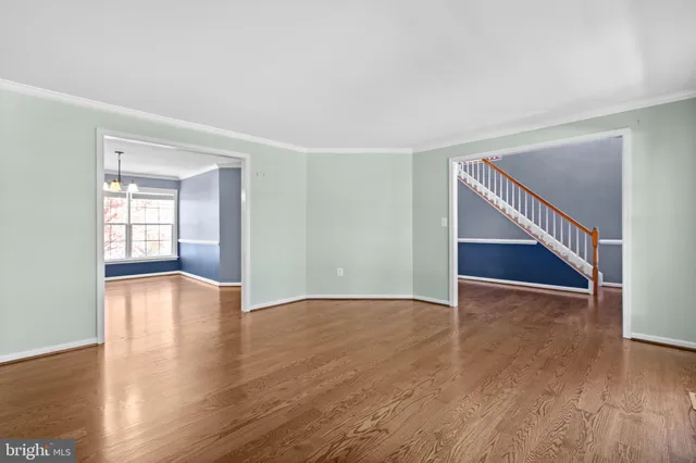 a view of an empty room with wooden floor and windows