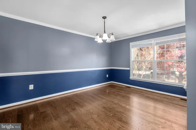 an empty room with wooden floor chandelier and windows