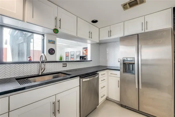 a kitchen with stainless steel appliances granite countertop a sink and a refrigerator