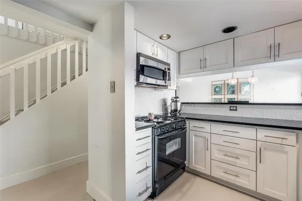 a kitchen with granite countertop white cabinets and stainless steel appliances