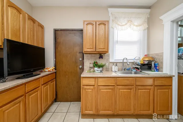 a room with two flat screen tv and a refrigerator