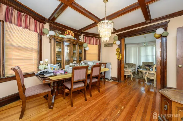 a dining room with wooden floor a chandelier a wooden table and chairs