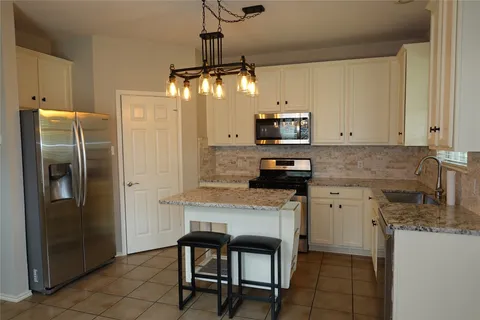 a kitchen with stainless steel appliances granite countertop a refrigerator a oven a sink a stove and a refrigerator
