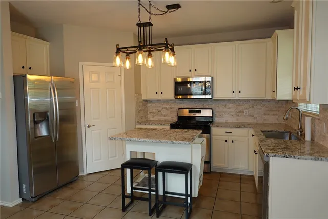 a kitchen with stainless steel appliances granite countertop a refrigerator a oven a sink a stove and a refrigerator