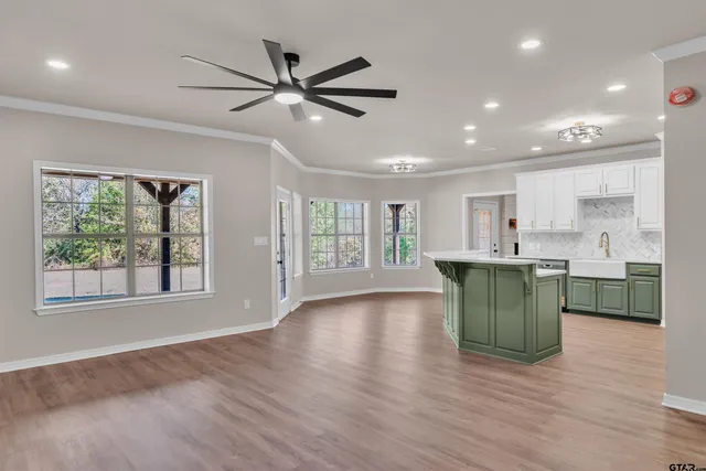 a view of an empty room with a kitchen and a window