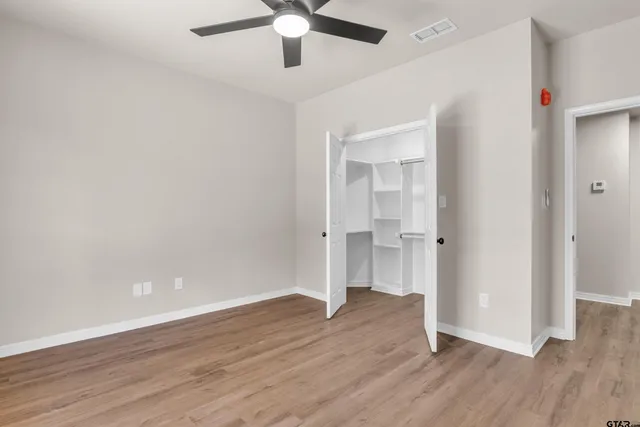 an empty room with wooden floor and ceiling fan