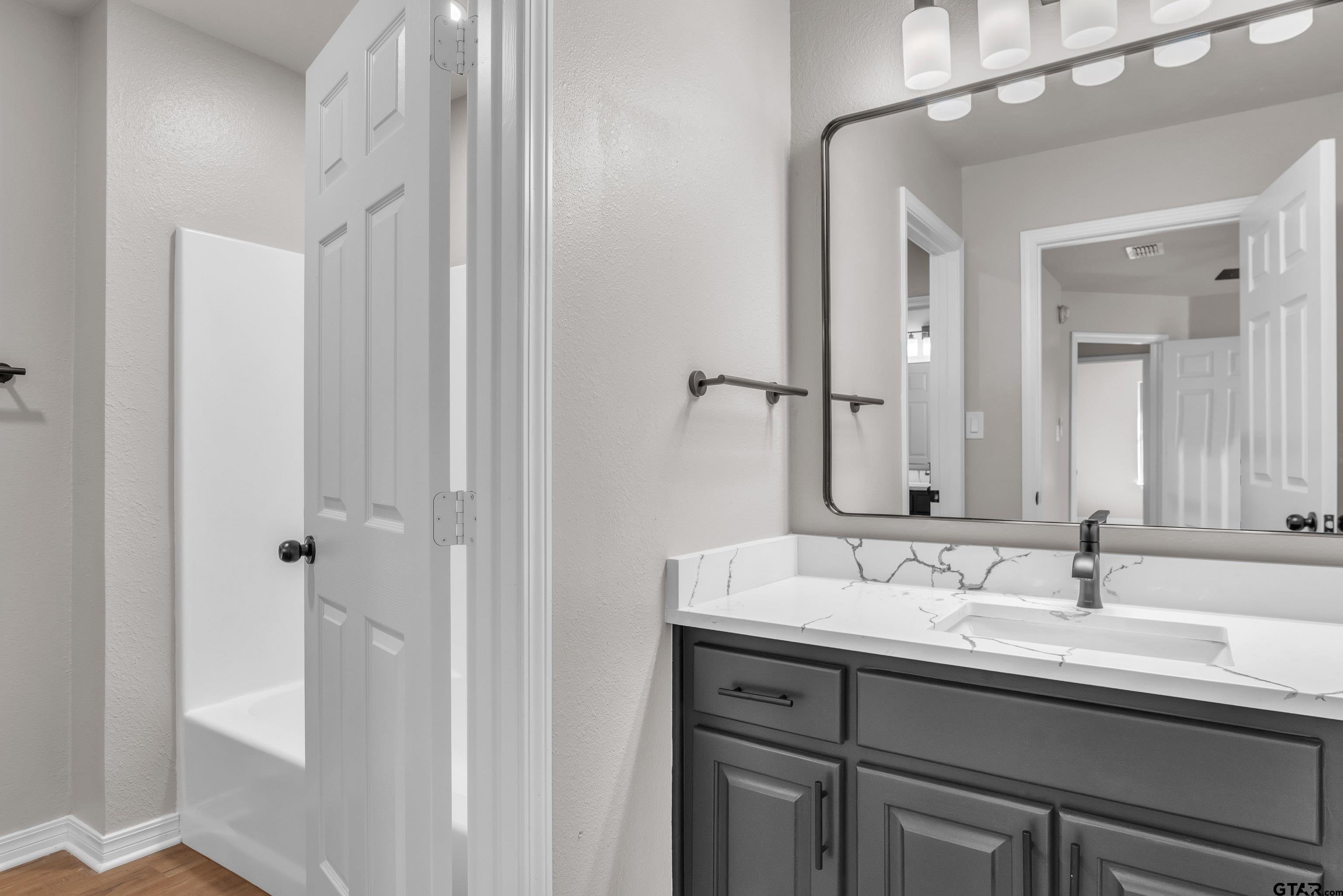 7589 Weeping Willow Road Big Sandy, TX 75755 - Photo 30 of 48 a bathroom with a double vanity sink a mirror and a shower