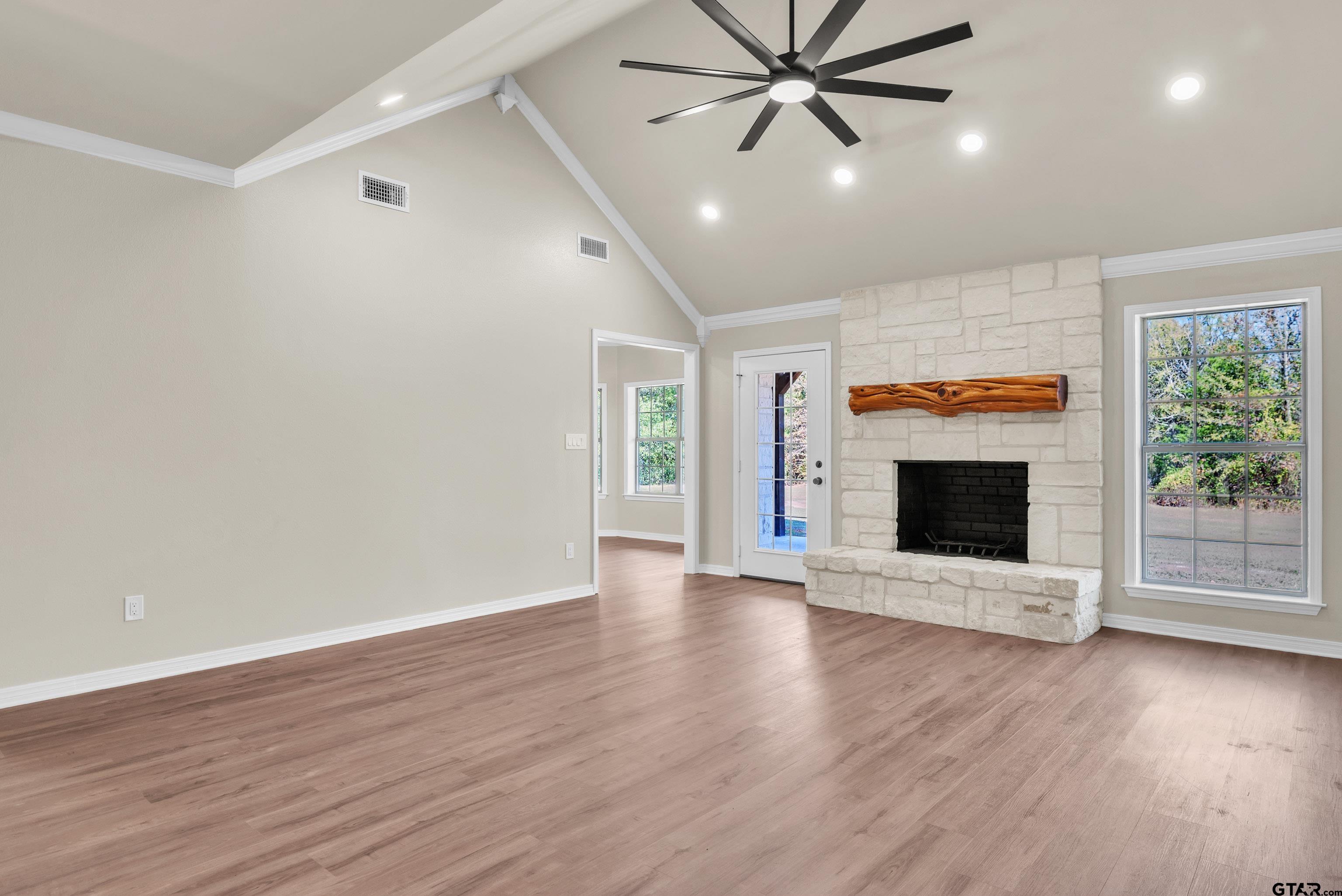 7589 Weeping Willow Road Big Sandy, TX 75755 - Photo 4 of 48 an empty room with wooden floor a fireplace and windows