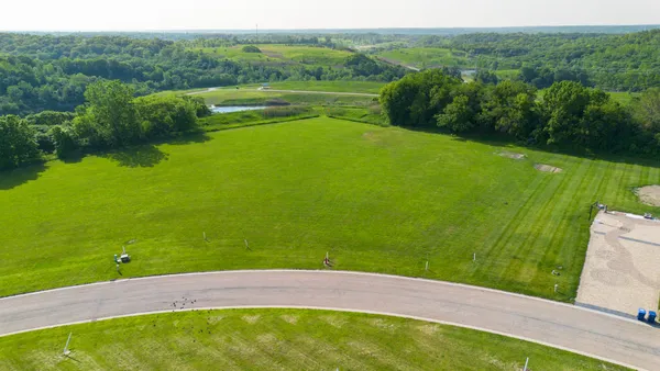 a view of a golf ground with huge green field and large trees
