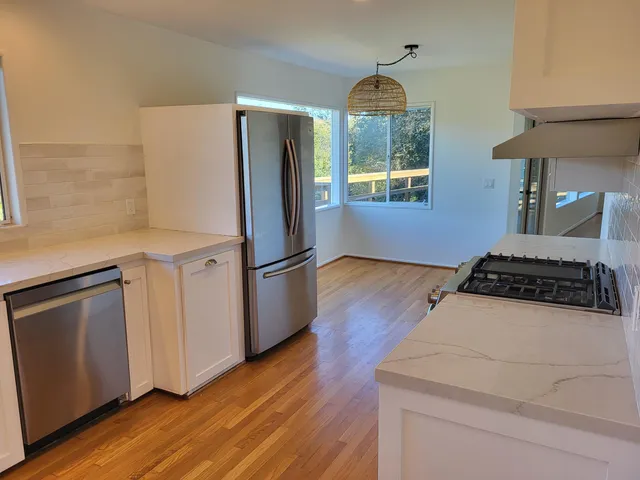 a kitchen with wooden floor white cabinets and stainless steel appliances