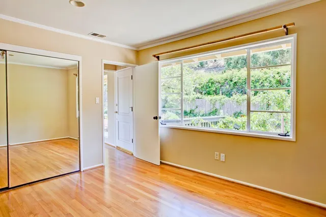 a view of empty room with wooden floor and fan