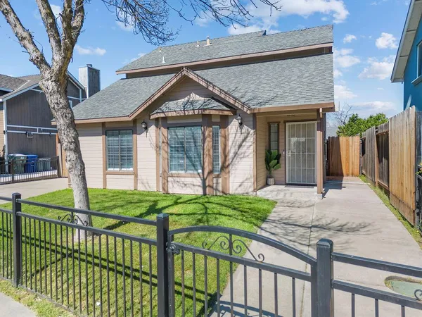 a view of a house with a small yard and wooden fence