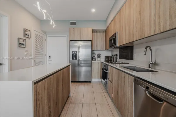a kitchen with stainless steel appliances a refrigerator a sink and white cabinets