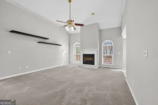 an empty room with windows fireplace and fans