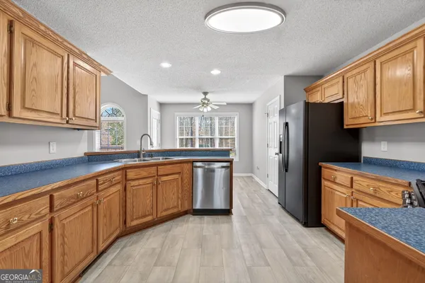 a kitchen with stainless steel appliances granite countertop a refrigerator a sink dishwasher and wooden cabinets with wooden floor
