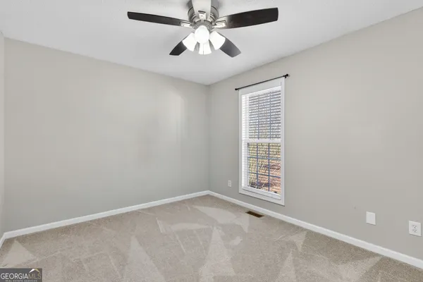 a view of an empty room with window and chandelier fan