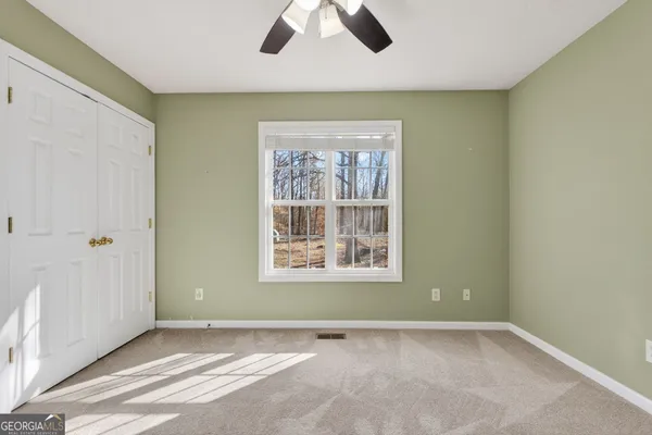 an empty room with chandelier fan and windows