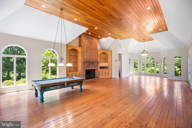 a room with wooden floor pool table and windows