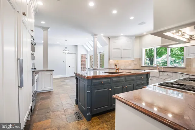 a kitchen with kitchen island granite countertop a sink a counter top space and stainless steel appliances