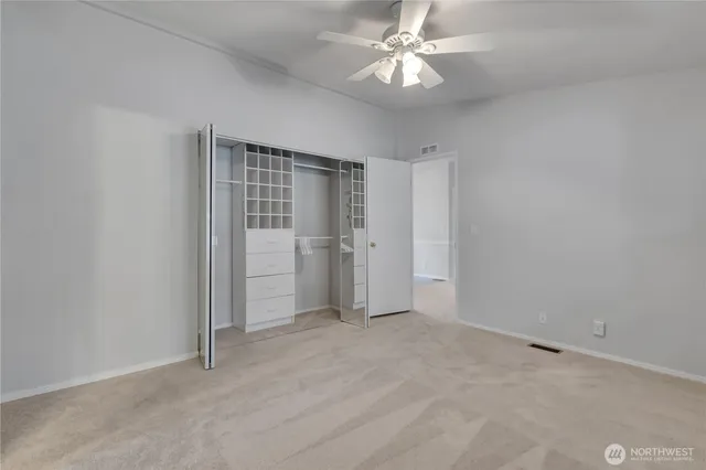 an empty room with a ceiling fan and carpet