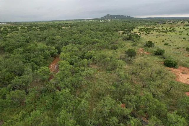 an aerial view of a houses with outdoor space and trees all around