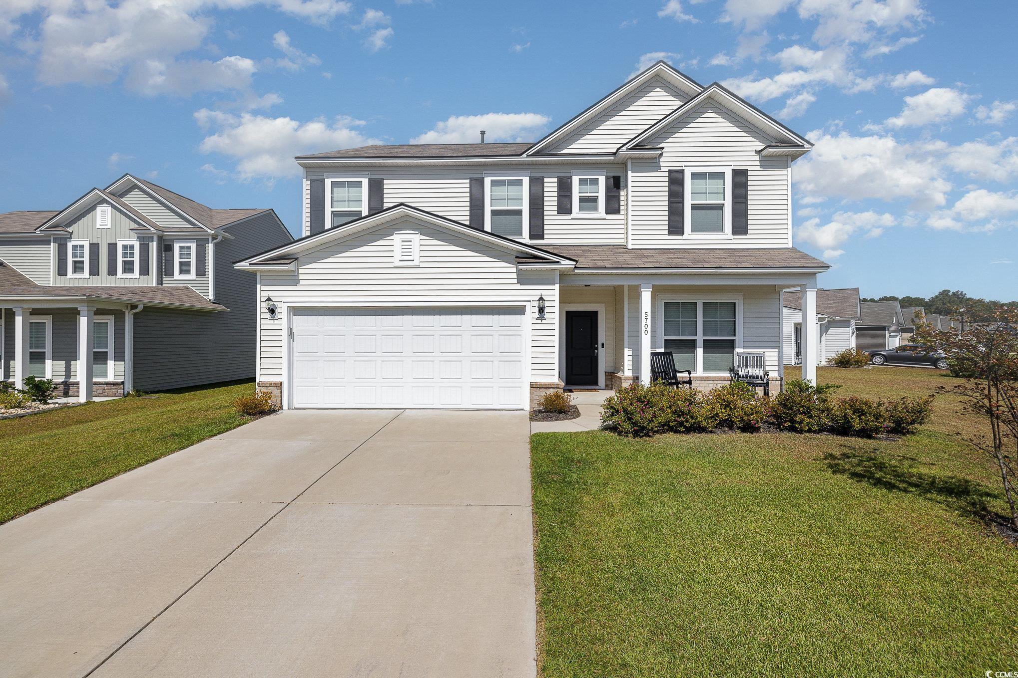 View of front facade featuring a porch, a front lawn, and a garage