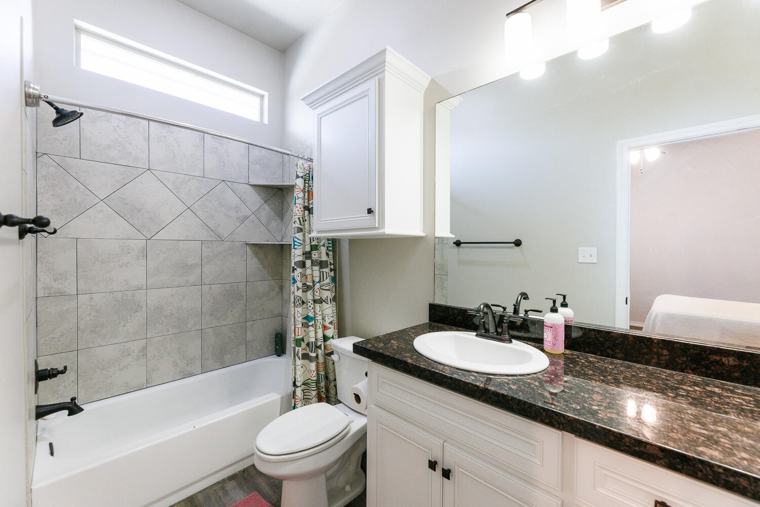 7619 59th Street Lubbock, TX 79407 - Photo 24 of 33 a bathroom with a granite countertop sink a toilet a mirror and bathtub