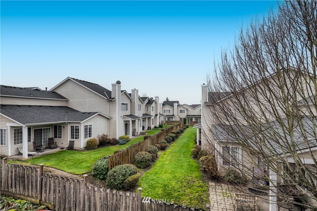2750 Diamond Loop, Unit E Milton, WA 98354 - Photo 13 of 13 a view of a house in front of a yard with plants and wooden fence