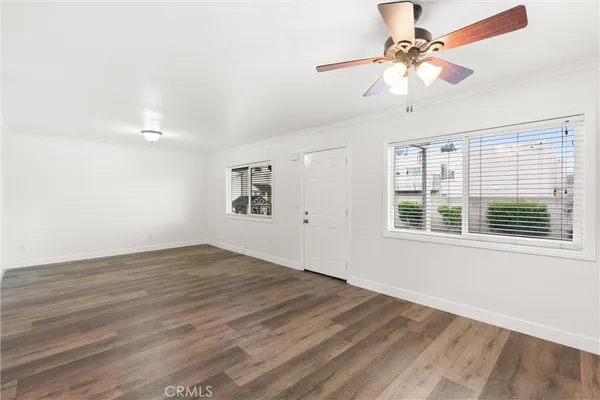 an empty room with wooden floor fan and windows