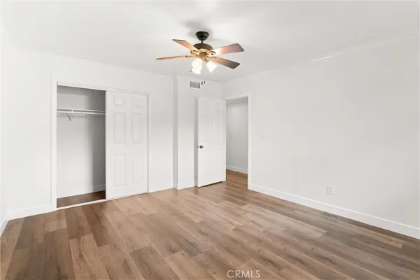 a view of empty room with wooden floor and ceiling fan