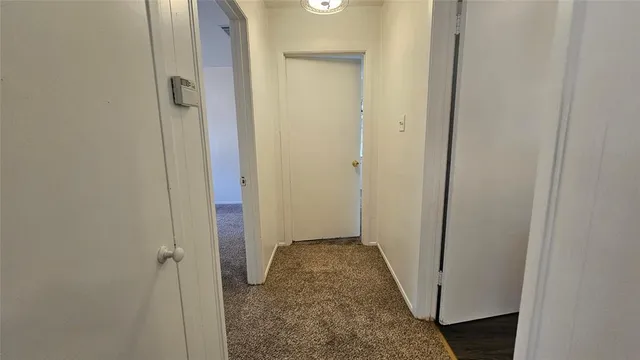 a view of a hallway with wooden floor and a bathroom